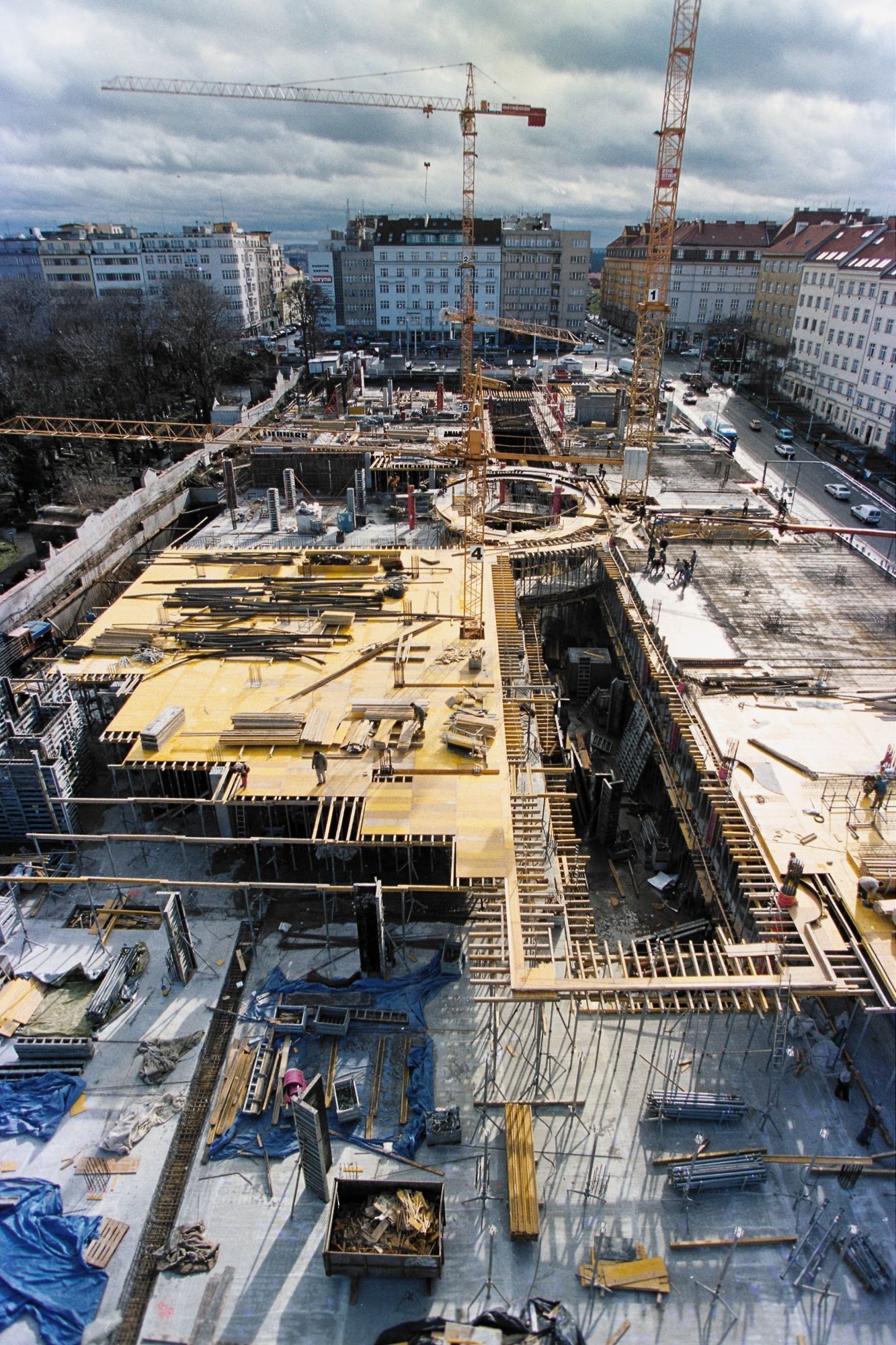 The footprint from above mid-build — the circular rotunda ring set into the slab, the anchor taking its place at the Flora corner over the metro.